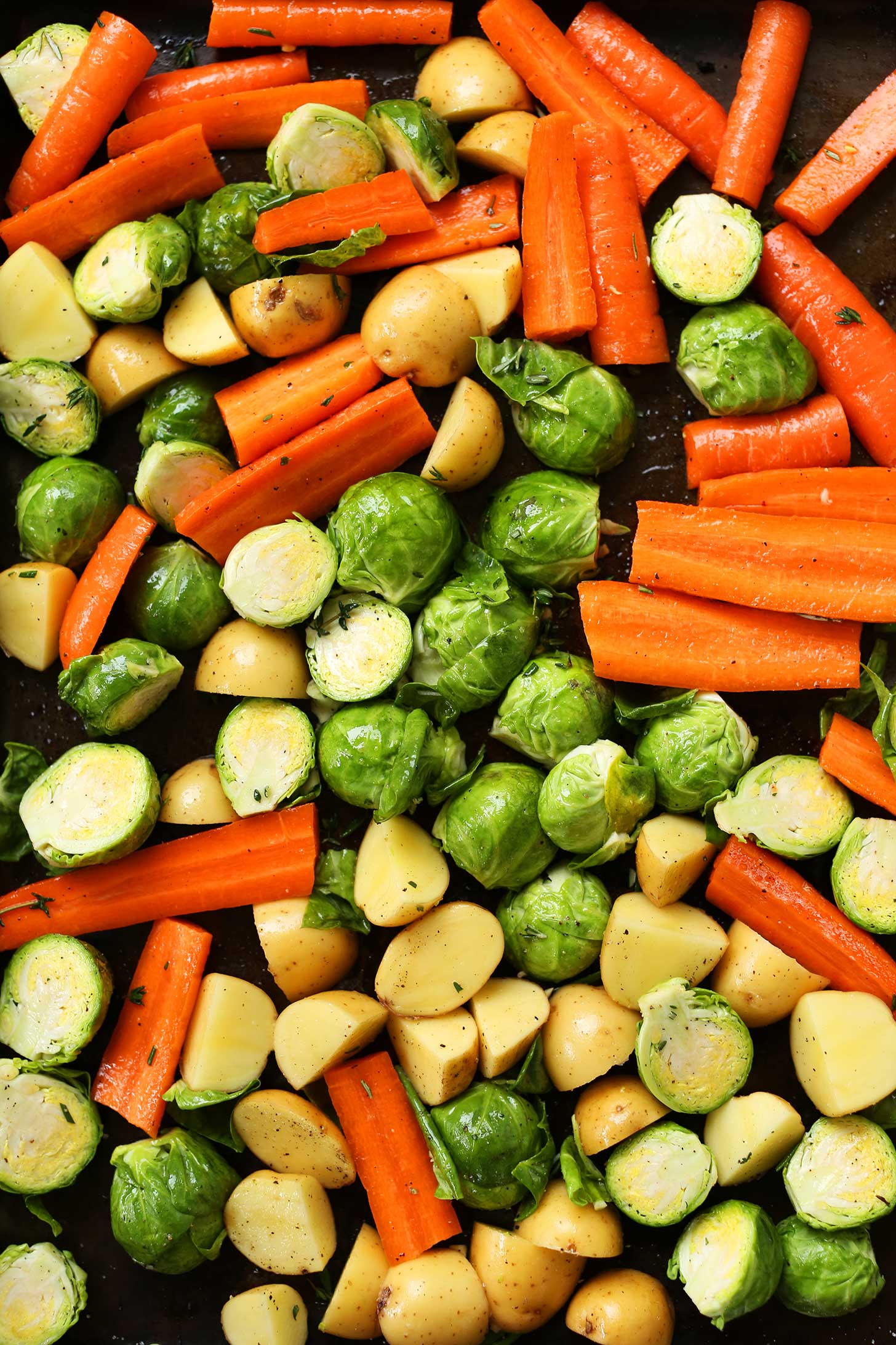 Baking sheet with potatoes, carrots, and Brussels sprouts ready for roasting
