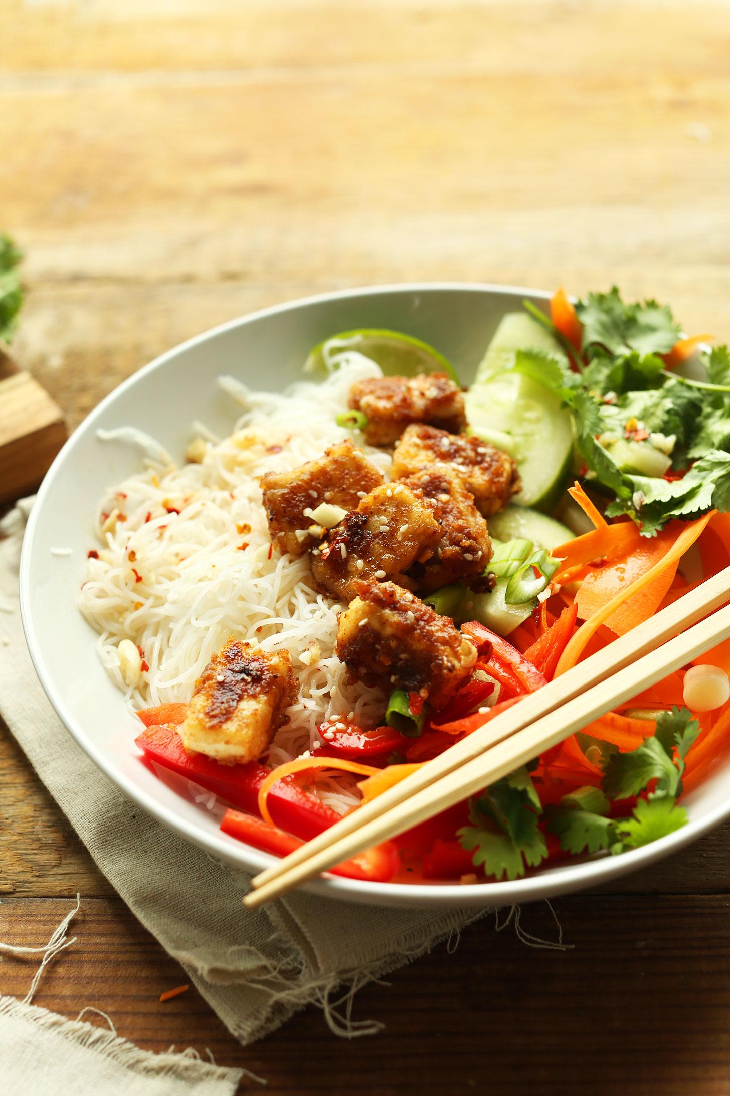 Chopsticks resting on a gluten-free vegan Thai Noodle Bowl with Crispy Almond Butter Tofu