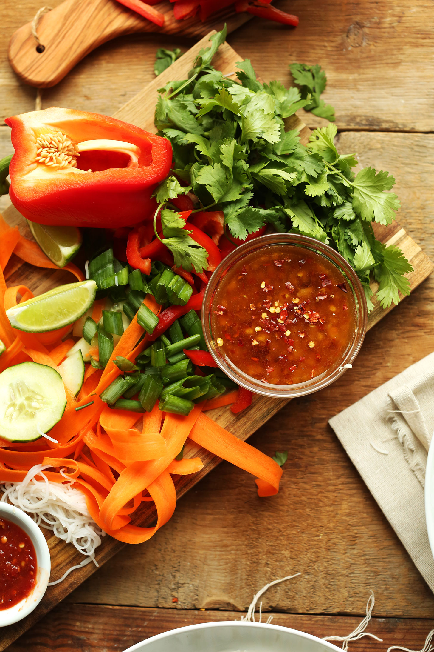 Wood cutting board with ingredients for making Thai Noodle Bowls for a fresh vegan recipe