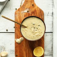Bowl of simple homemade Vegan Caesar Dressing on a cutting board