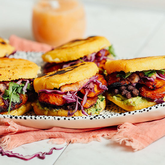 Tray of Vegan Arepa Sandwiches with a jar of hot sauce in the background