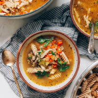 Bowls of chicken noodle soup topped with fresh parsley
