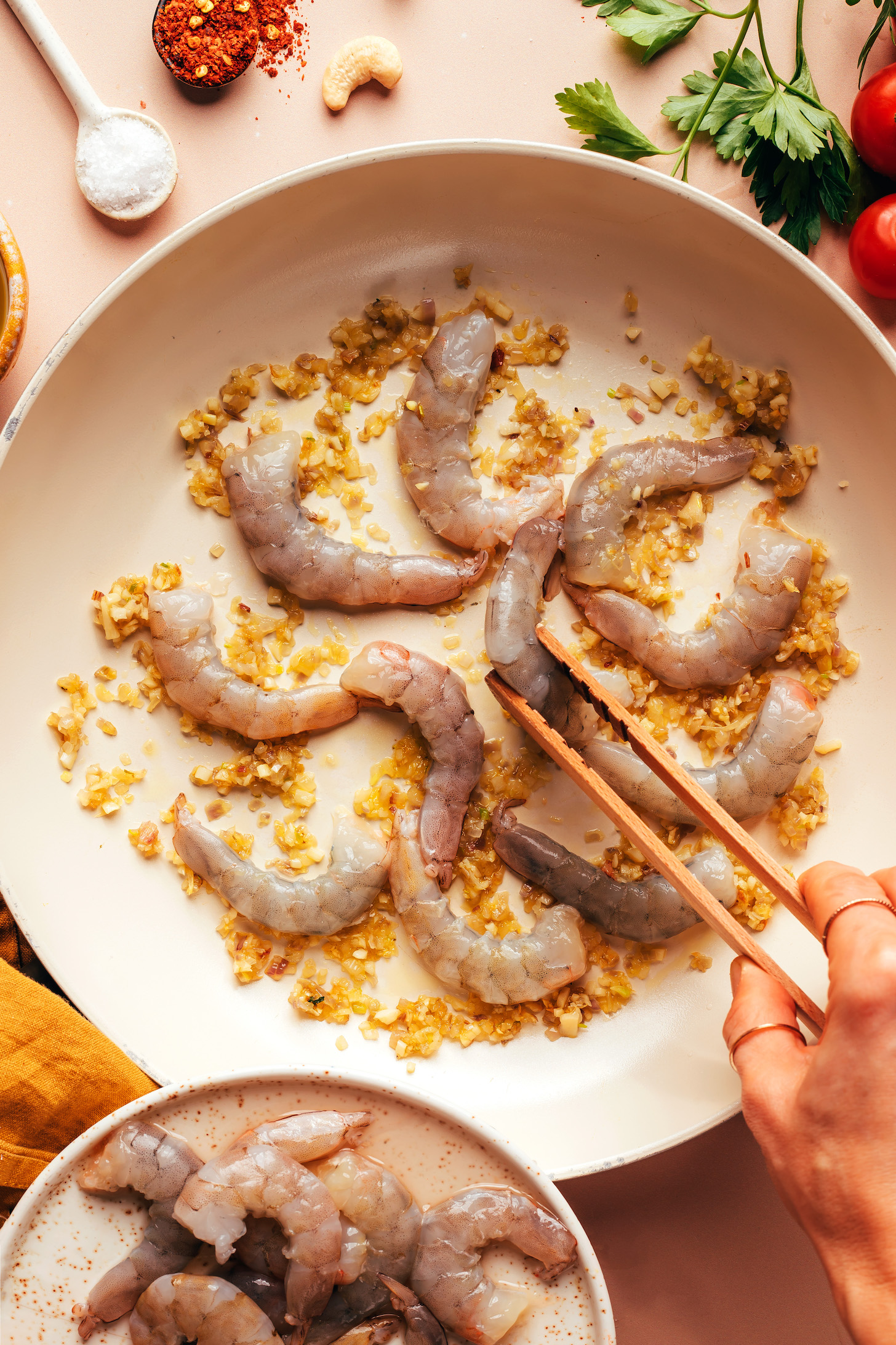 Cooking raw shrimp in a skillet with sautéed garlic and shallot