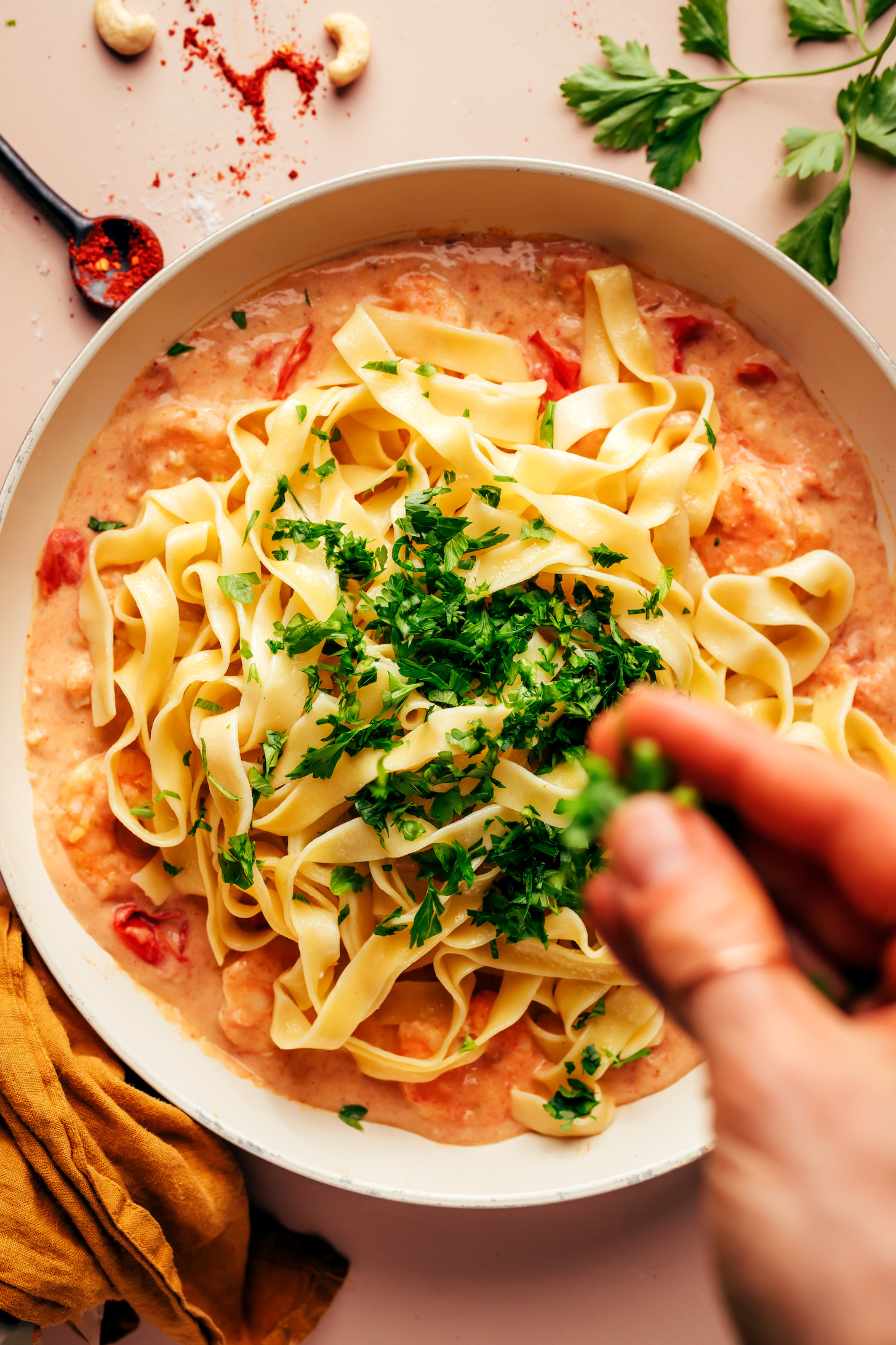 Sprinkling fresh parsley over pasta