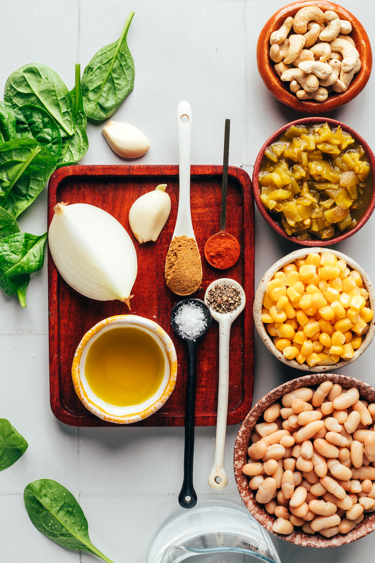 Baby spinach, garlic, onion, olive oil, cumin, cayenne, black pepper, salt, white beans, corn, green chiles, and cashews