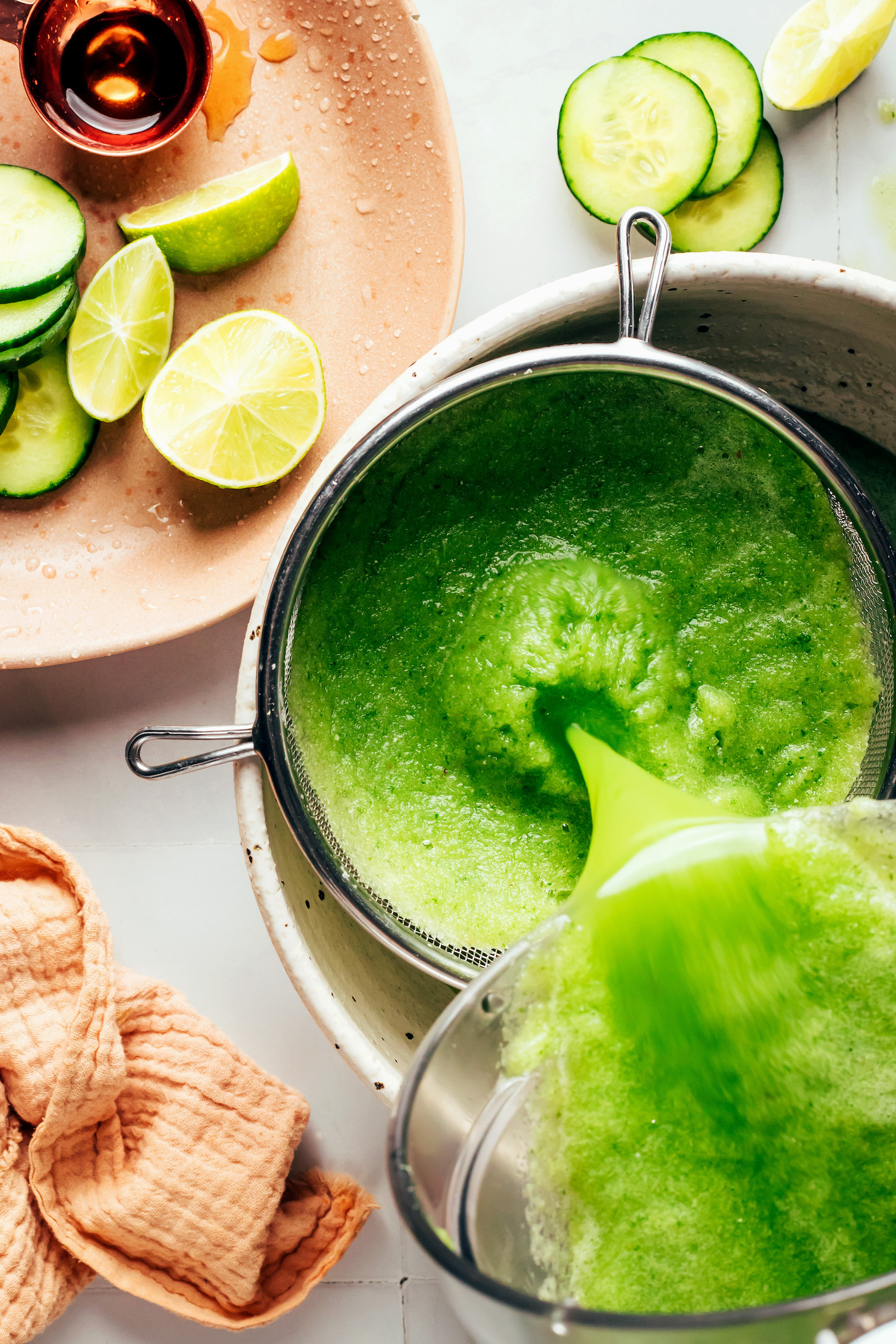 Straining a blended cucumber lime mixture through a fine mesh strainer