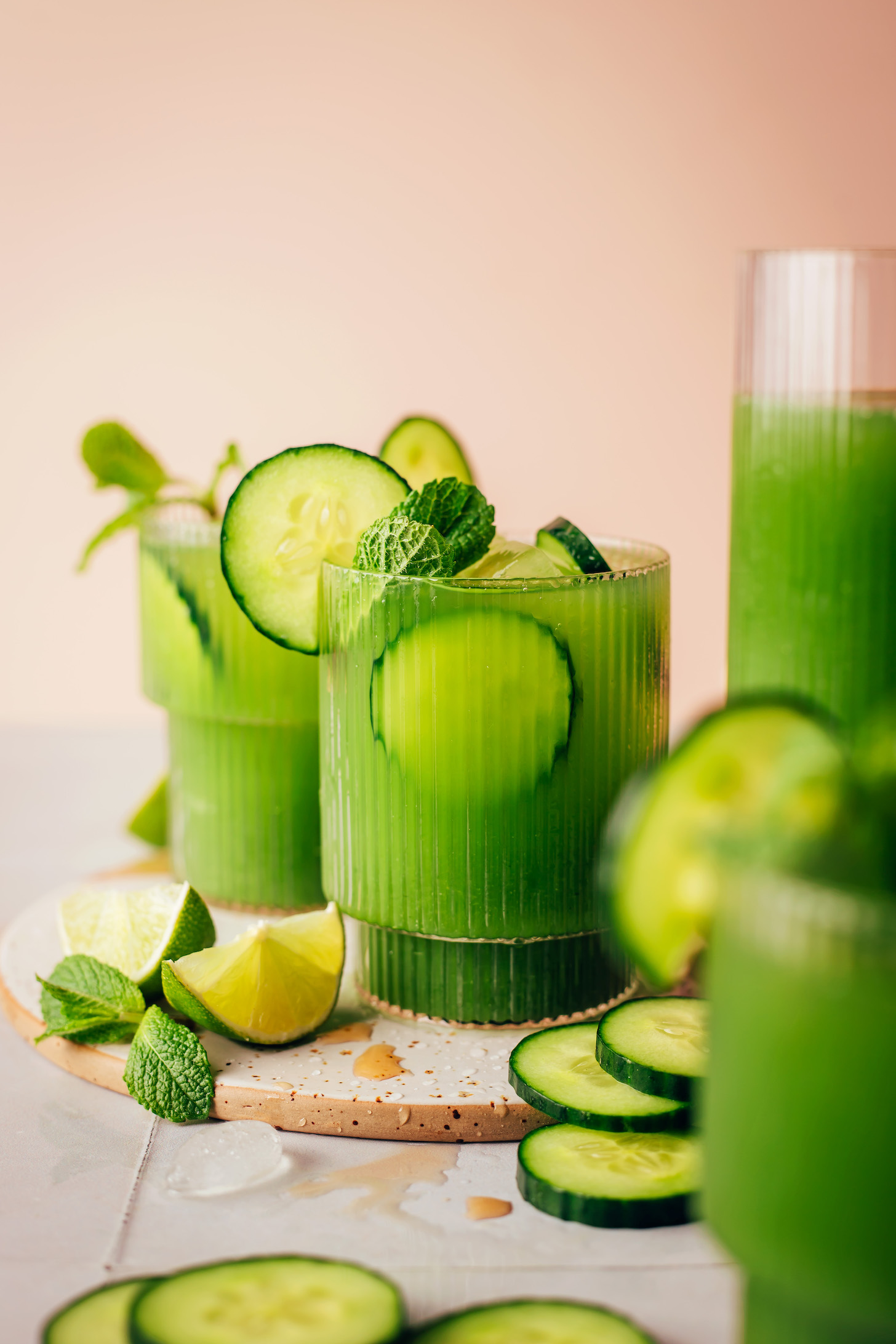 Side view of glasses of cucumber lime agua frescas with sliced cucumbers and fresh mint