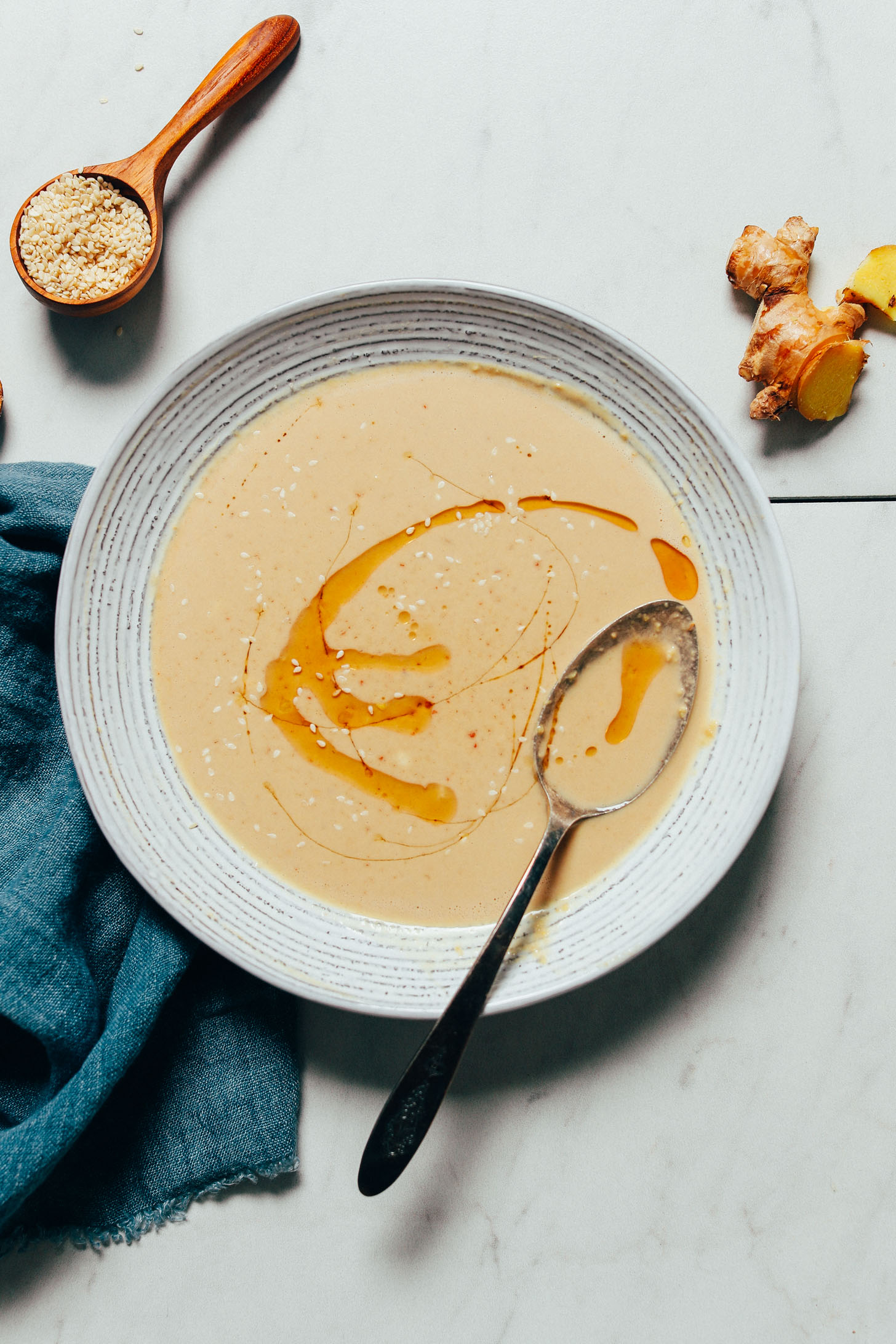 Bowl of our Ginger Garlic Miso Tahini Dressing with a swirl of toasted sesame oil in it
