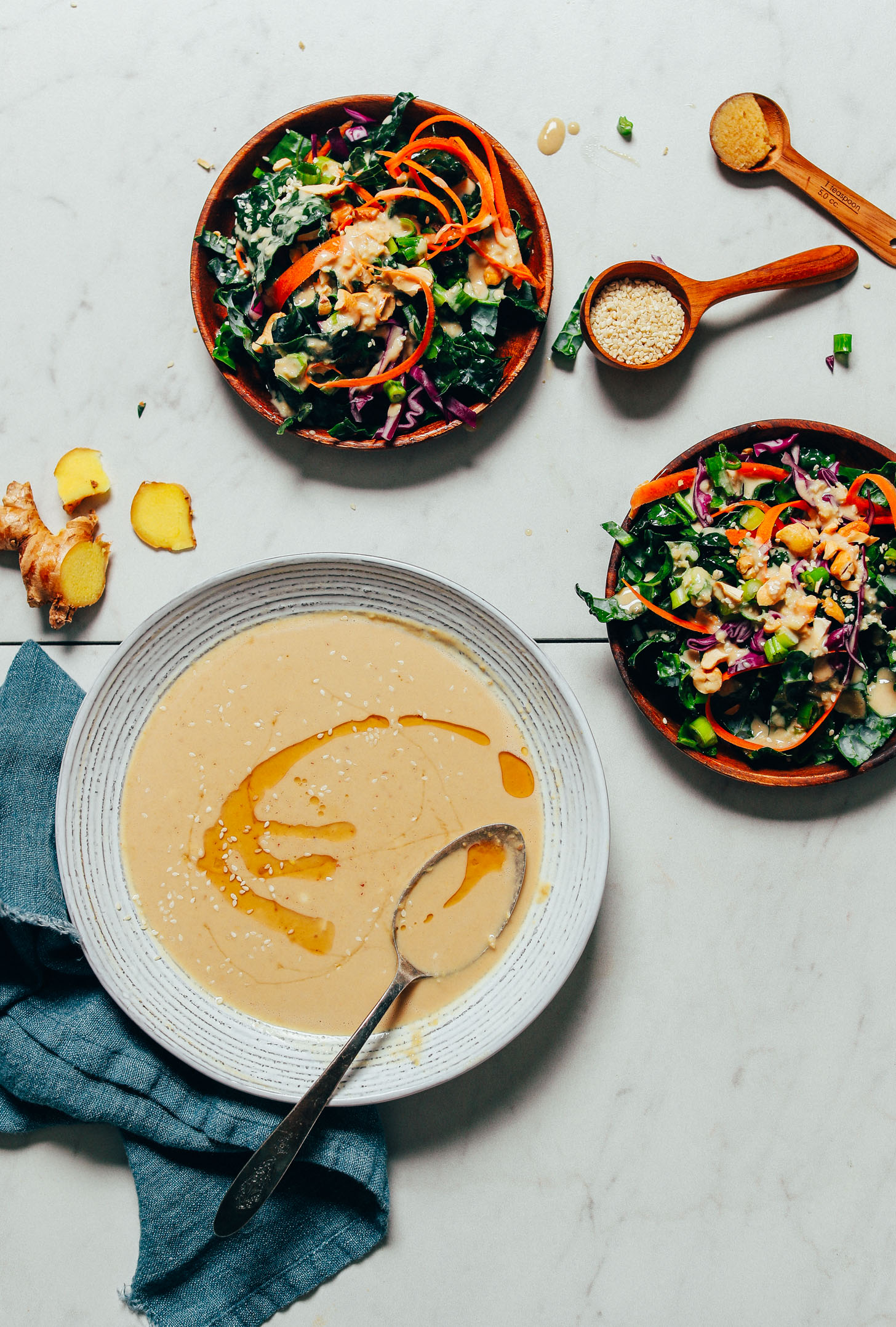 Bowl of Ginger Garlic Miso Tahini Dressing beside plates of kale salad
