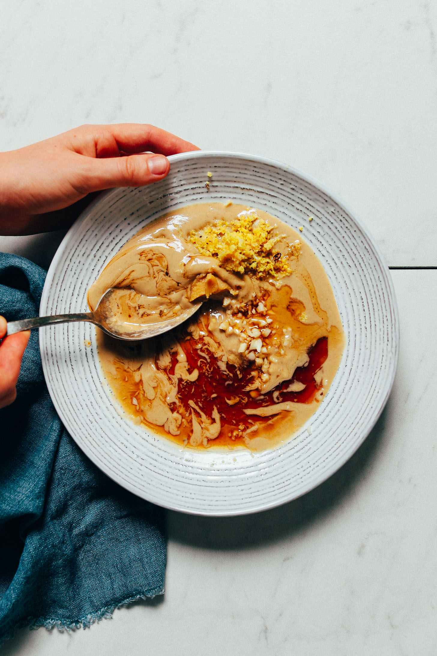 Using a large spoon to stir ingredients for our Ginger Garlic Miso Tahini Dressing recipe
