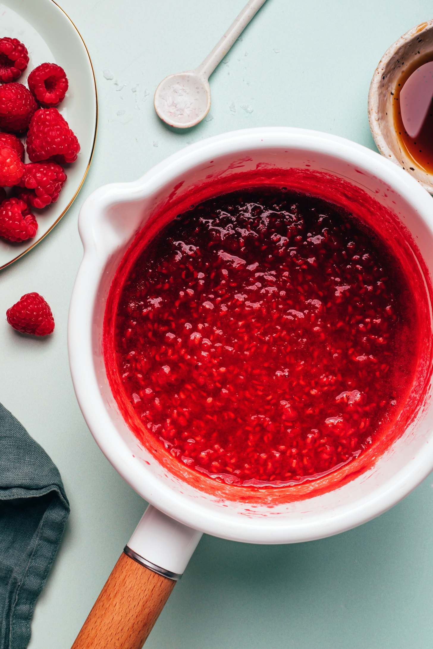 Saucepan of homemade raspberry compote next to ingredients used to make it