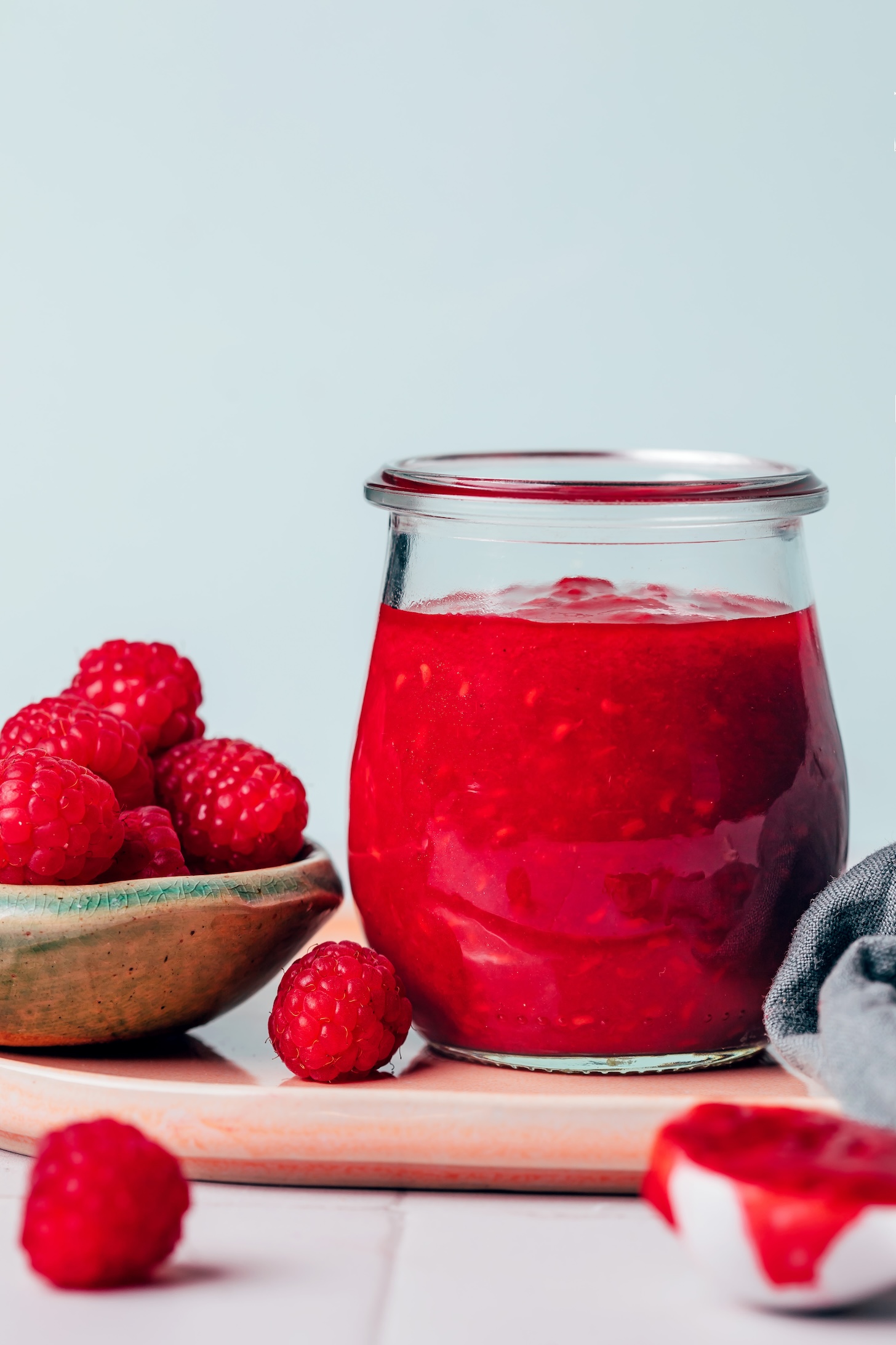 Bowl of fresh raspberries next to a jar of raspberry compote