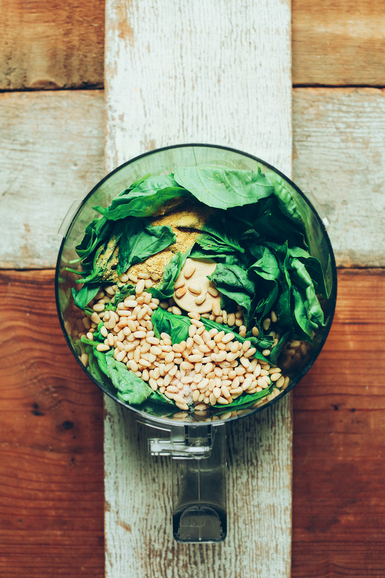 Food processor filled with ingredients for making homemade gluten-free vegan basil pesto