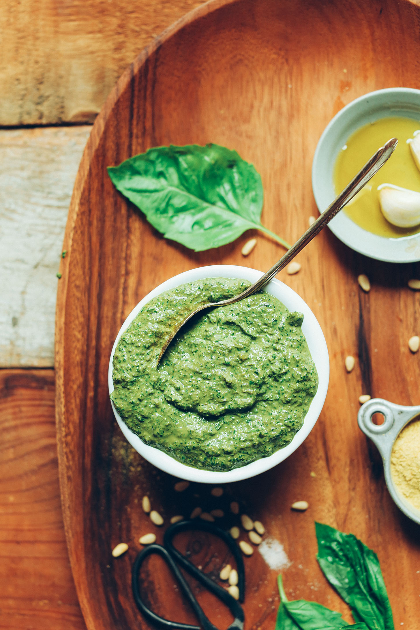Bowl of our easy Vegan Pesto on a wood platter with ingredients used to make it