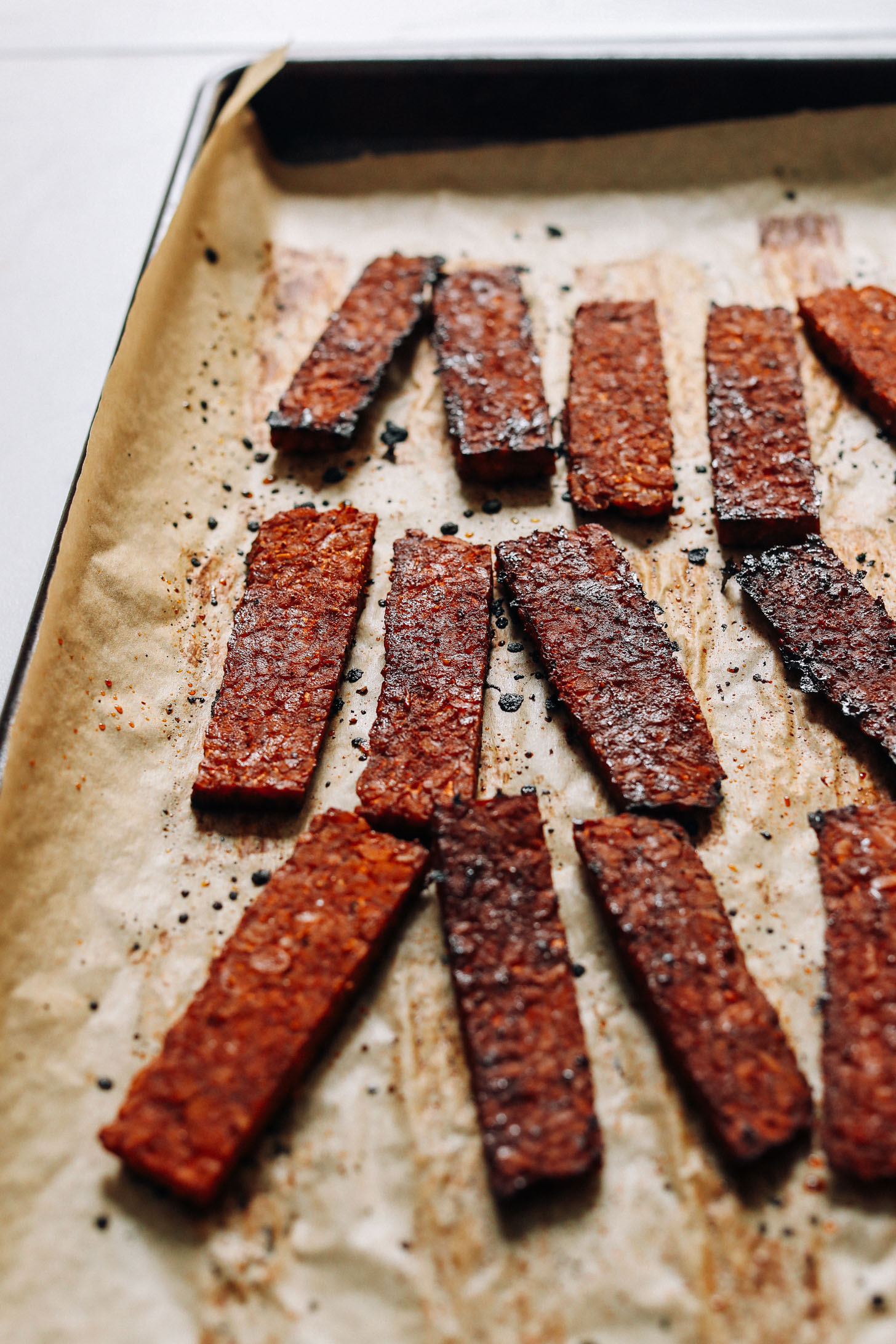 Strips of crispy tempeh bacon on a baking sheet