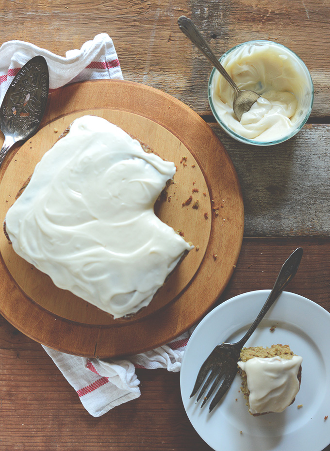 Plate and cutting board with Gluten-Free Zucchini Cake and a bowl of extra frosting