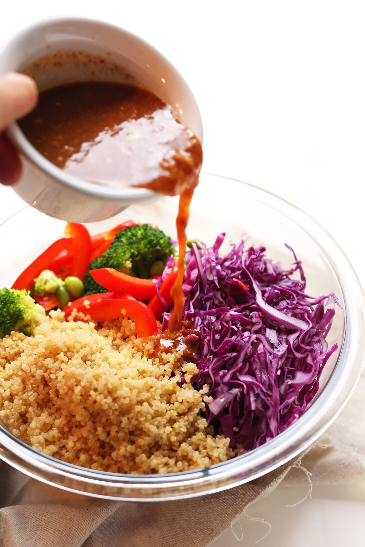 Pouring dressing over our Asian Inspired Rainbow Quinoa Salad for a protein- and fiber- rich plant-based meal
