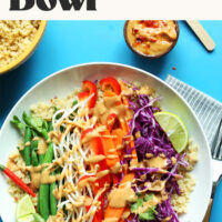 Bowl of quinoa gado gado next to smaller bowls of quinoa and homemade peanut sauce