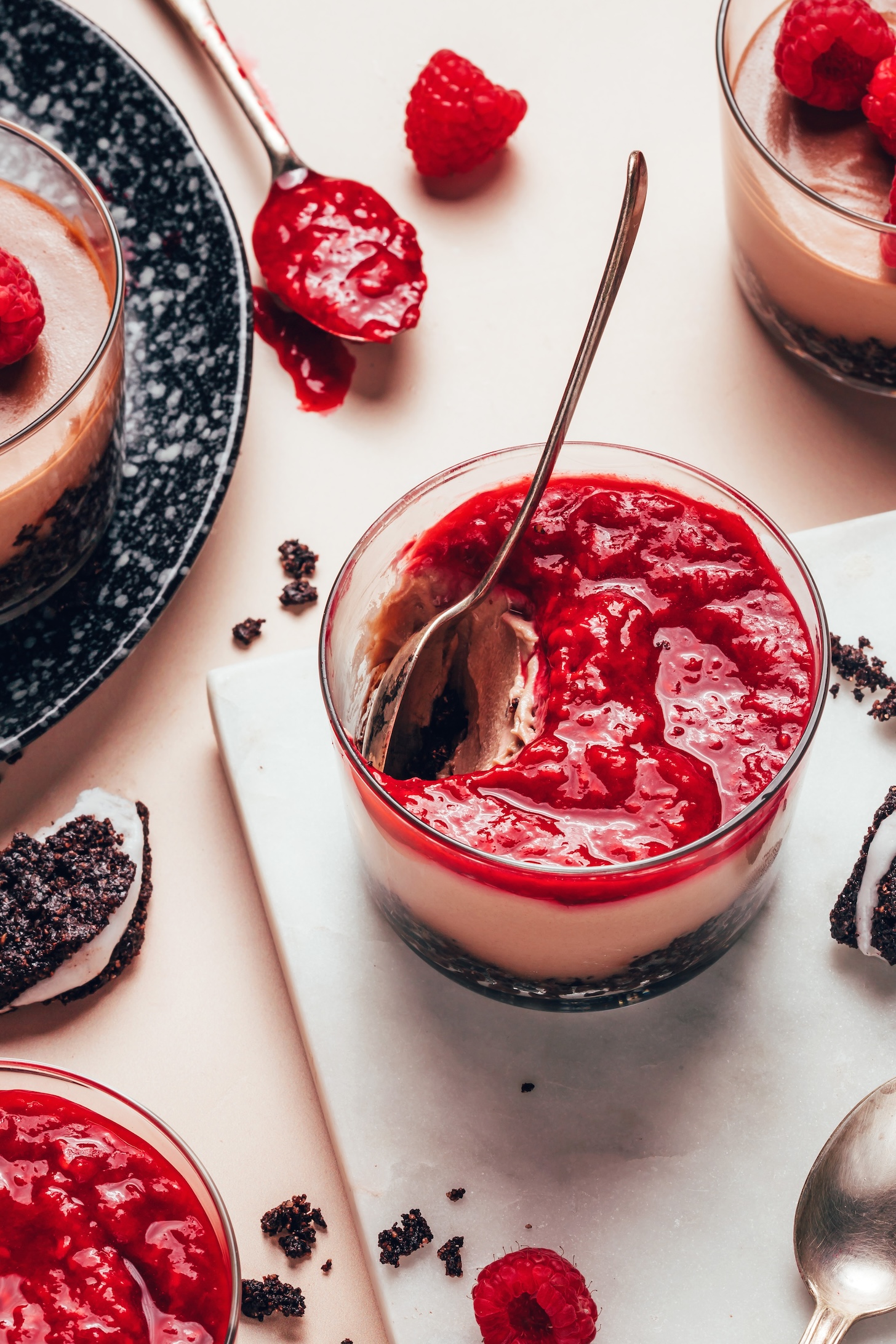 Spoon resting in a glass dessert jar filled with no-bake chocolate cheesecake and raspberry compote
