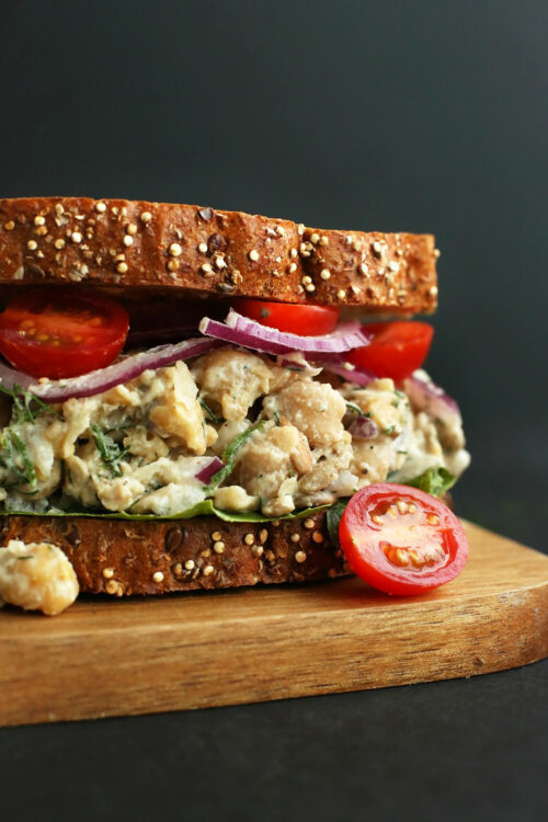 Photo of a chickpea sunflower sandwich on a wood cutting board