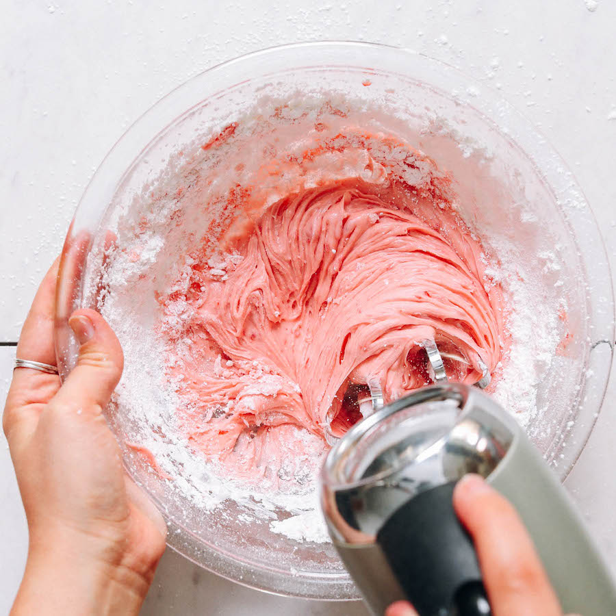 Spreading vegan strawberry frosting on a cake